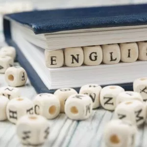 Word english made with block wood letters next to a pile of other letter over wooden table