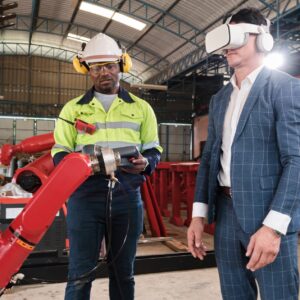 Black engineer demonstrates robotic arm control to a customer with a vr headset.